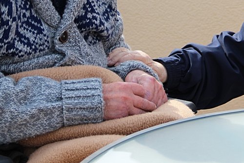 Eine Hand liegt beruhigend auf dem Arm eines älteren Menschen