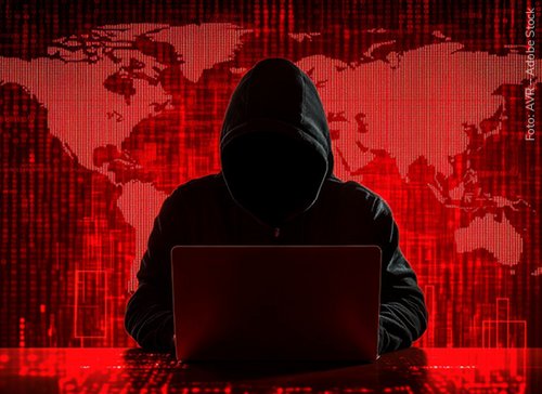 Mann mit Kapuze vor einem Laptop - zum Blogbeitrag: Überall und mit allen Mitteln: Unternehmen im Fadenkreuz von hybrider Kriegsführung