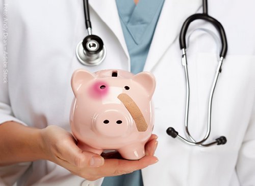 Arzt mit einem Sparschwein in der Hand - zum Blogbeitrag: Finanzielle Schwierigkeiten: Sanierung? Ja, aber mit Plan!