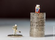 Zwei Stapel Geldmünzen mit Spielfiguren oben auf