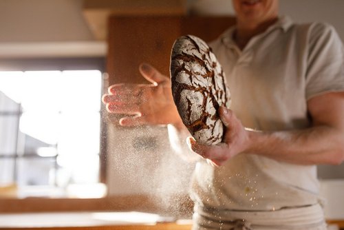 Bäcker der ein Krustenbrot in der Hand hält und das Mehl abklopft - zum Blogbeitrag: Traditionsbäckerei Neff saniert sich in Eigenverwaltung