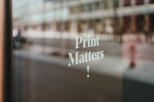 Fensterscheibe durchscheinendem weißen Schriftzug Print Matters!