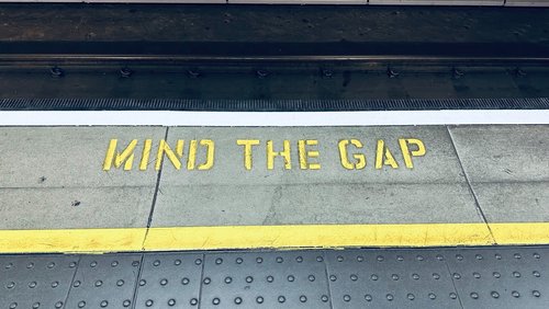 Gelber Schriftzug auf dem Boden einer Bahnstation "Mind the Gap" - zum Blogbeitrag: Insolvenz-Vorsorge für die betriebliche Altersvorsorge