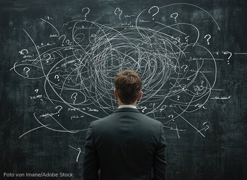 Mann steht vor Wand mit vielen Fragezeichen - zum Blogbeitrag: Eine Branche vor großen Herausforderungen: (Erste) allgemeine Verunsicherung