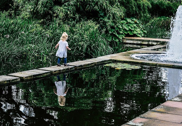 Kind läuft Richtung Brunnen 